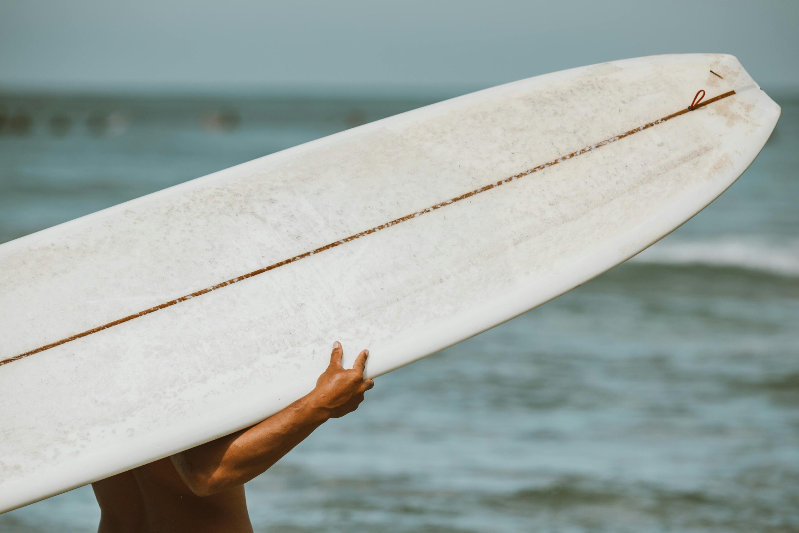 pexels-photo-4608711-4608711 Close-up of a surfer carrying a surfboard on a beach in Hawaii.